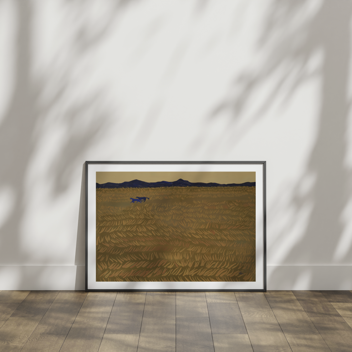 Framed artwork of a landscape with mountains and a field on a white wall.
