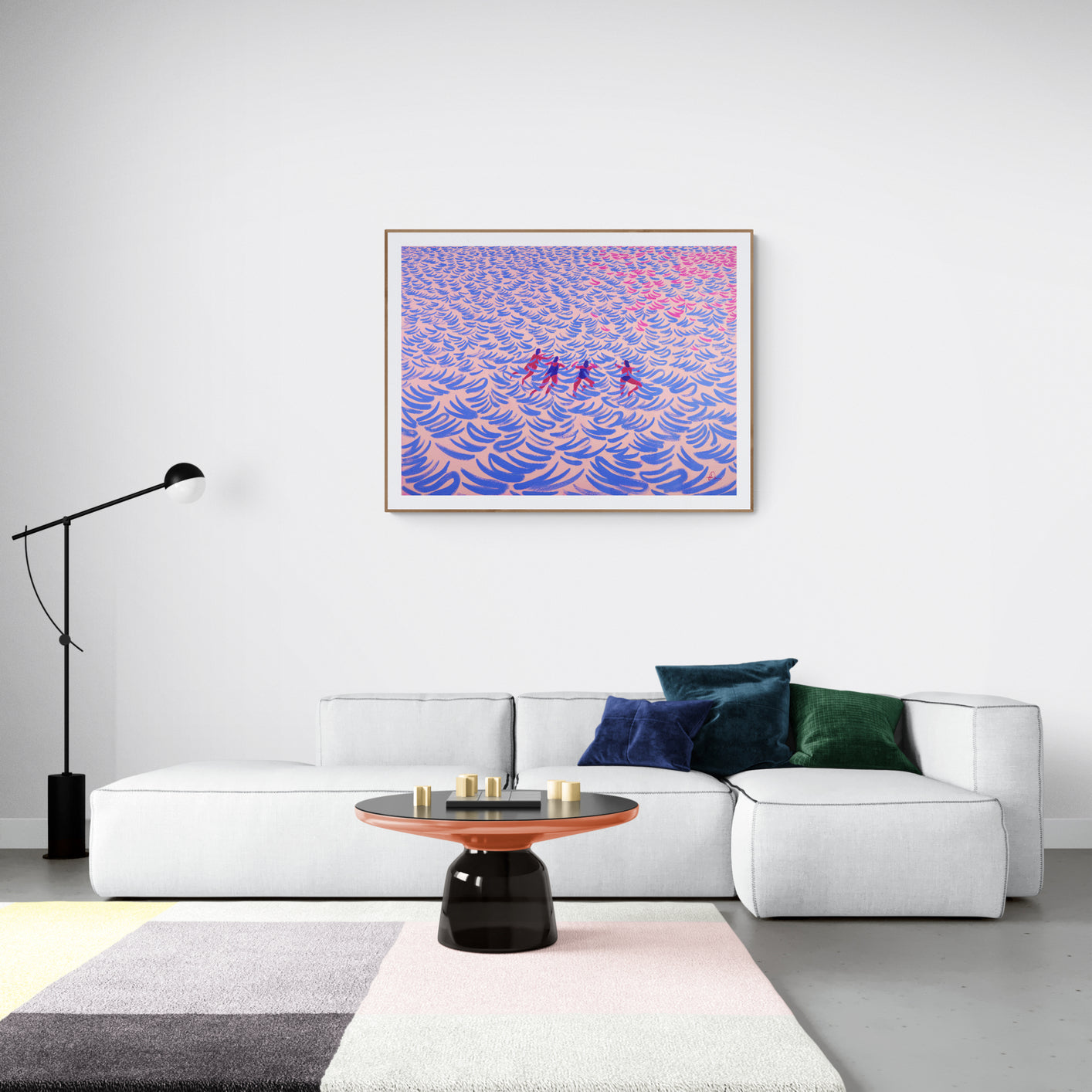 A framed abstract art print featuring peple swimming in the ocean on a white wall in a minimalist living room setting.